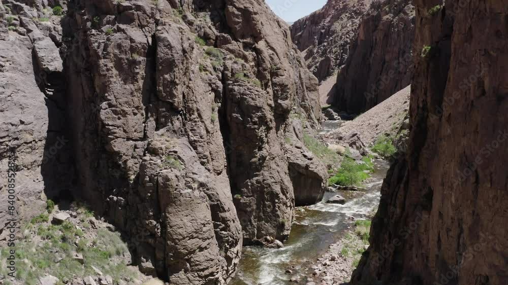 A drone captures a breathtaking view of towering cliffs surrounding a serene river gorge, bathed in the glow of midday sunlight. The rugged beauty of owens river gorge. A drone captures a breathtaking view of towering cliffs surrounding a serene river gorge, bathed in the glow of midday sunlight. The rugged beauty of owens river gorge.