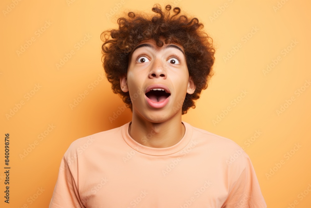 Teenage boy of mixed ethnicity, expressing amazement on a gentle peach background Teenage boy of mixed ethnicity, expressing amazement on a gentle peach background