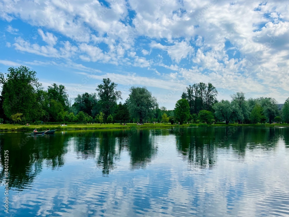 Green trees and sky reflection on the water surface, pond in the park