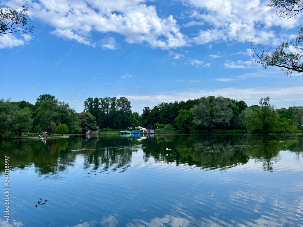 Green trees and sky reflection on the water surface, pond in the park Green trees and sky reflection on the water surface, pond in the park
