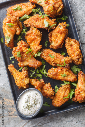 Crispy Curry Chicken Wings served with greek yogurt closeup on the plate on the marble table. Vertical top view from above