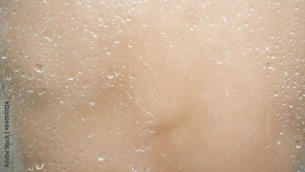 Man Behind Glass in Shower Washing and Turning Under Water Stream, Out of Focus.