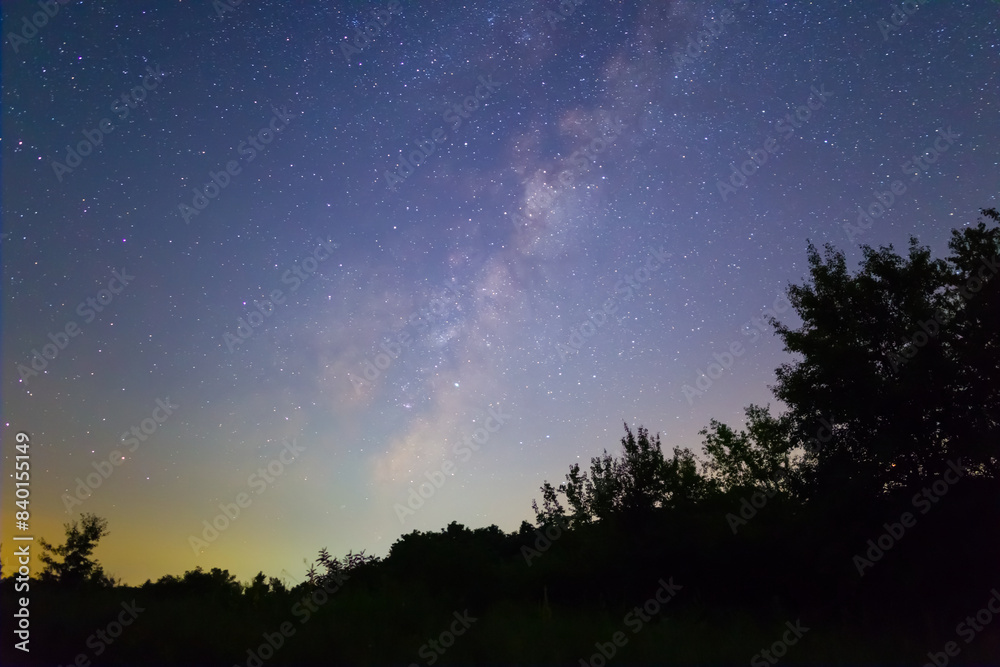 milky way on night starry sky above a forest silhouette