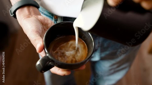 Preparation, Top view person's hand is using a pitcher to pour milk foam to make a hot coffee latte. Making homemade coffee at home. Close up slow motion video