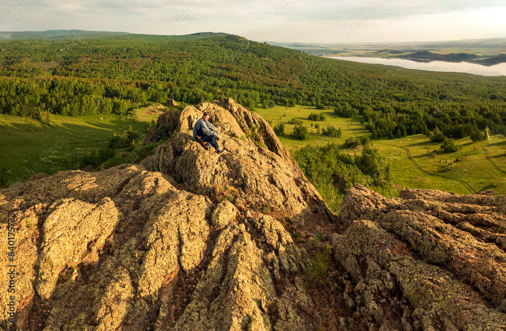 Naklejka premium a young handsome man travels through the mountains of the Southern Urals on a summer day