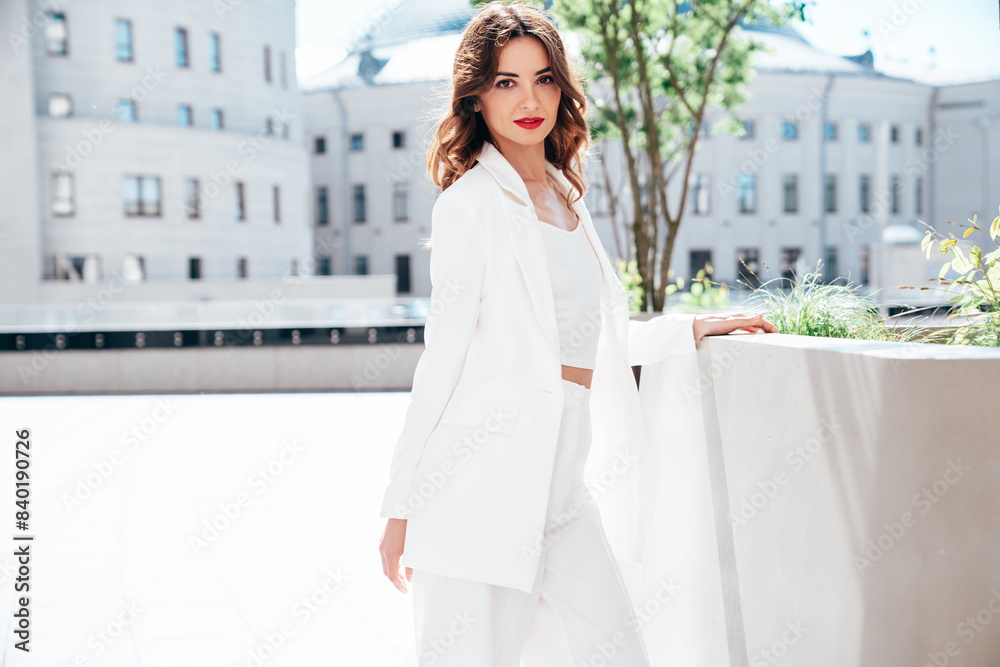 Fototapeta premium Young beautiful brunette woman wearing nice trendy white suit jacket. Sexy smiling model posing in the street at sunny day. Fashionable female outdoors. Cheerful and happy. Evening makeup, red lips