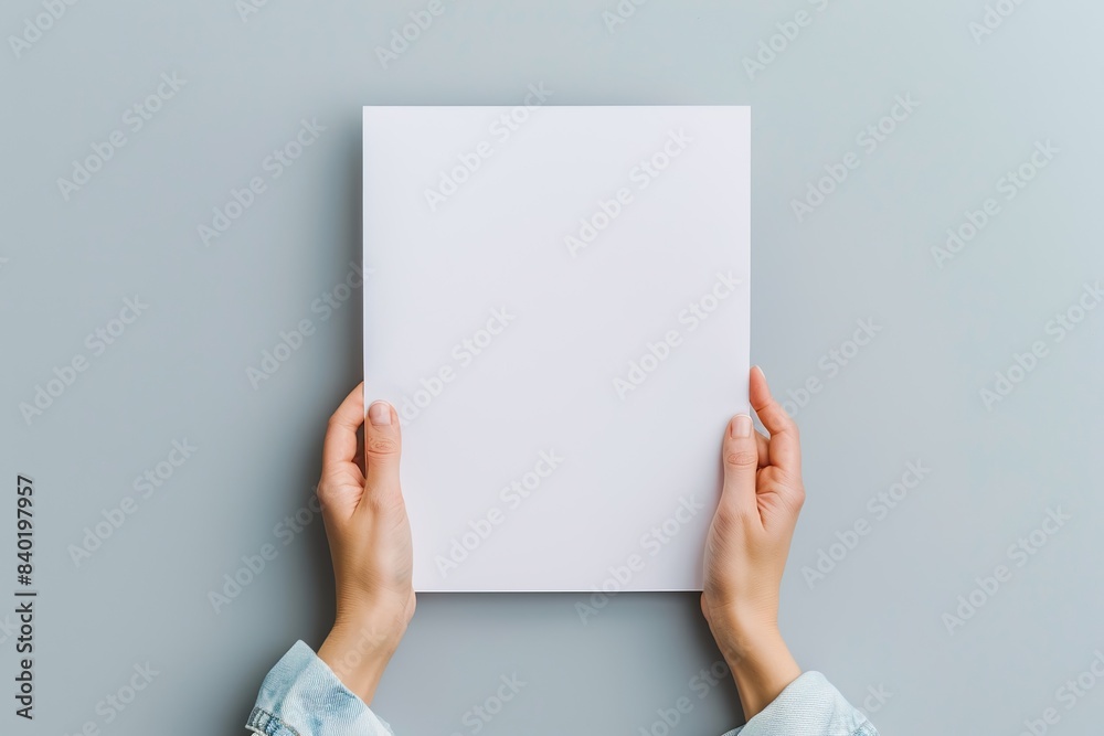 hands holding a blank paper sheet on a gray background in a top view mockup for artwork or design with copy space hands holding a blank paper sheet on a gray background in a top view mockup for artwork or design with copy space