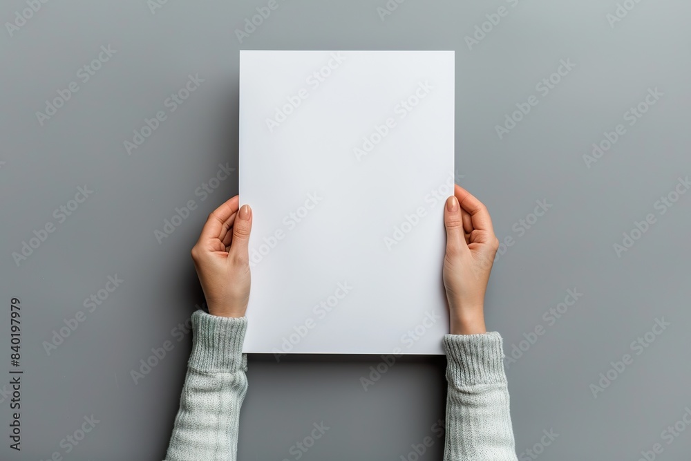 hands holding a blank paper sheet on a gray background in a top view mockup for artwork or design with copy space hands holding a blank paper sheet on a gray background in a top view mockup for artwork or design with copy space