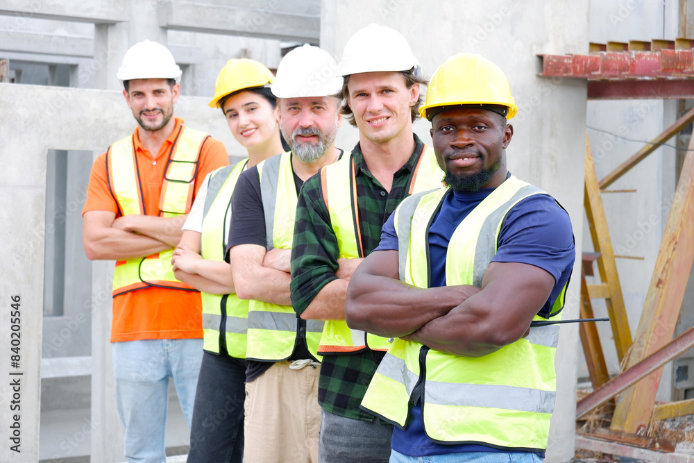 A team of male and female engineers stand smiling at a construction site for the housing industry. A team of male and female engineers stand smiling at a construction site for the housing industry.