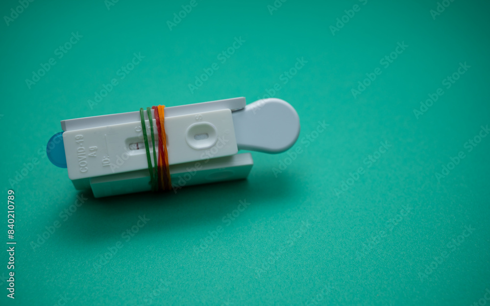 A few of Covid-19 rapid antigen test casettes tied with colorful rubber bands, isolated on green background. A close-up and selective focus photo of the test cassette. A few of Covid-19 rapid antigen test casettes tied with colorful rubber bands, isolated on green background. A close-up and selective focus photo of the test cassette.