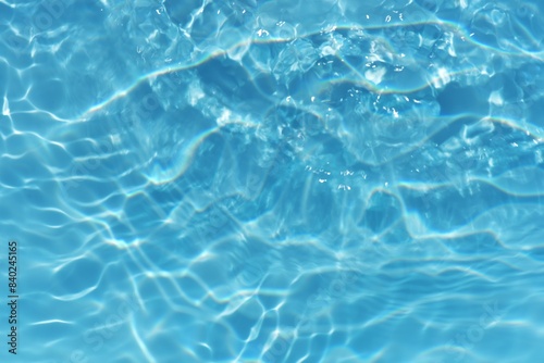Blue water with ripples on the surface. Defocus blurred transparent blue colored clear calm water surface texture with splashes and bubbles. Water waves with shining pattern texture background. 