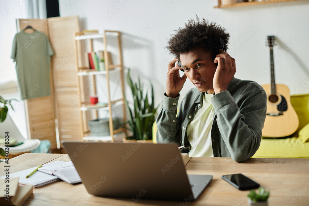 An African American man in headphones works diligently at his laptop. An African American man in headphones works diligently at his laptop.