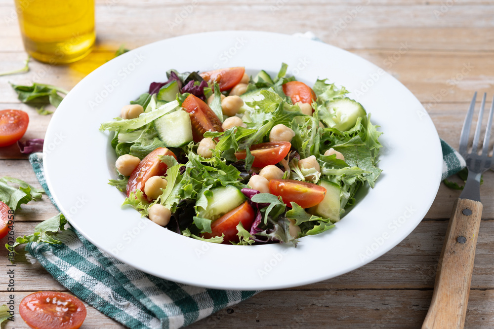 Healthy chickpea salad with tomato,lettuce and cucumber on wooden table Healthy chickpea salad with tomato,lettuce and cucumber on wooden table