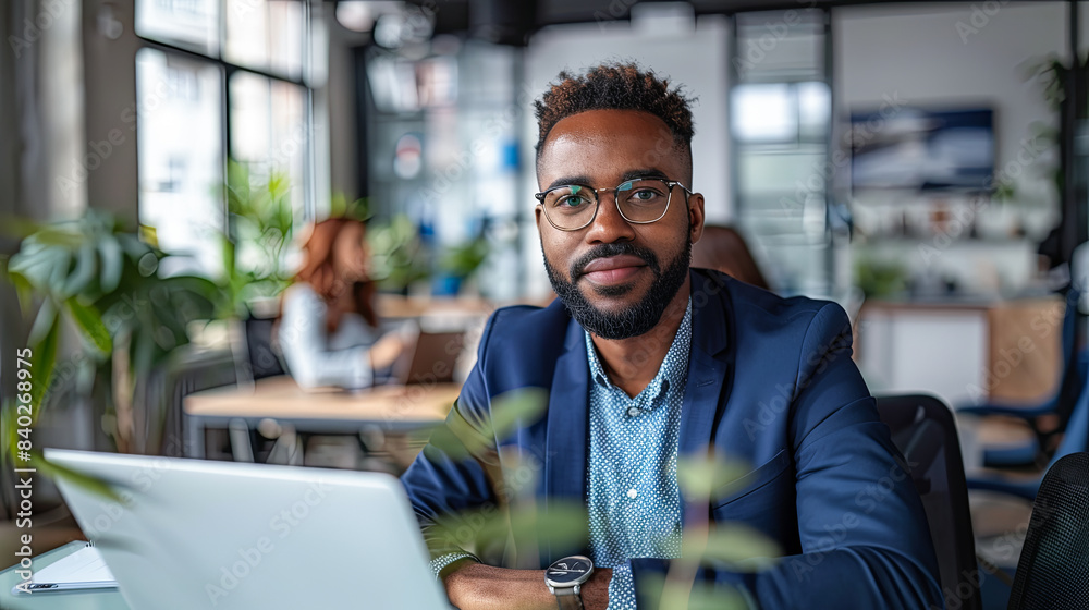 Fototapeta premium young african american businessman in eyeglasses using laptop in office