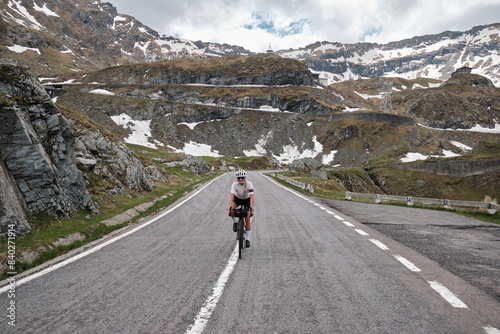 Woman cyclist riding a gravel bike with a view of the romanian mountains. Fit athlete wearing sportswear and helmet. Sports motivation image. Carpathian Mountains, Transfăgărășan road in Romania.