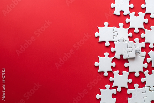A lot of white puzzles lie on red background. The concept of building a successful business piece by piece 