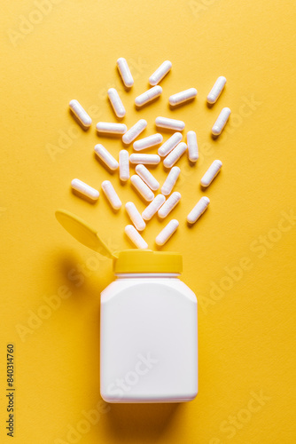 White medicine capsules on yellow background photo