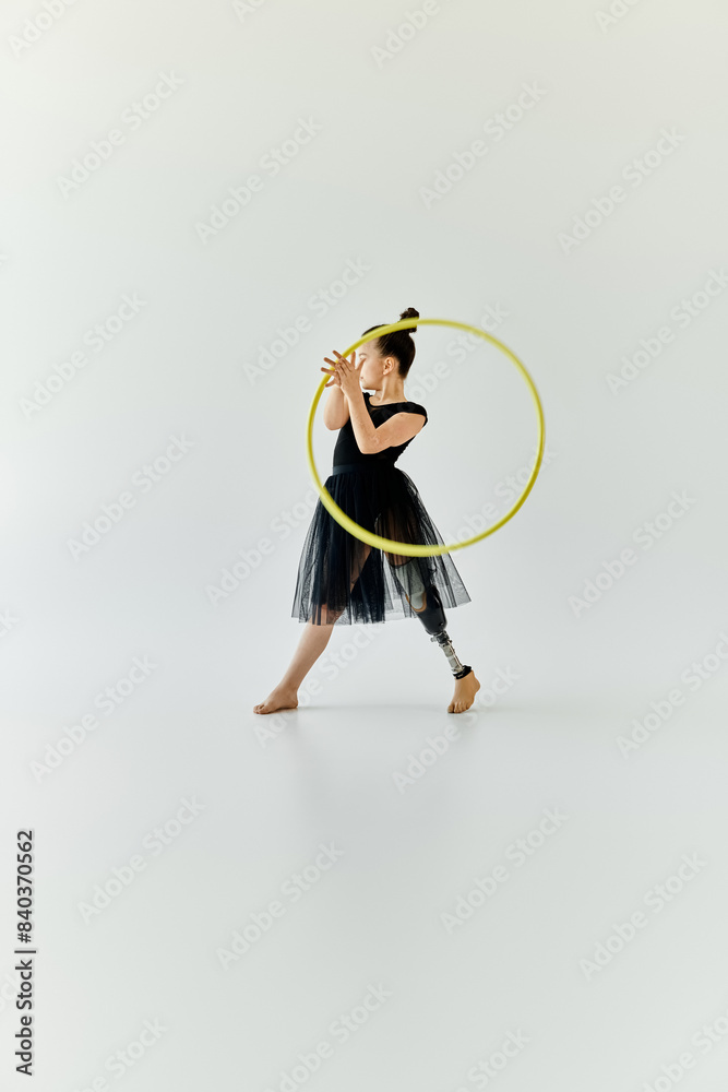 Fototapeta premium A young girl with a prosthetic leg performs gymnastics with a hula hoop.