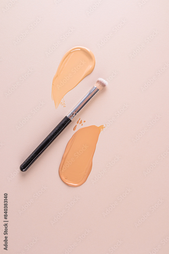 Two samples of liquid foundation powder in a natural tone and a makeup brush on a beige background. vertical top view. Layout for product design. Two samples of liquid foundation powder in a natural tone and a makeup brush on a beige background. vertical top view. Layout for product design.