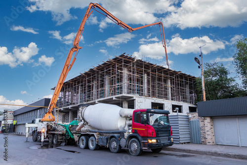 A concrete pump truck takes concrete from a concrete mixer truck and pours the floor at a construction site.