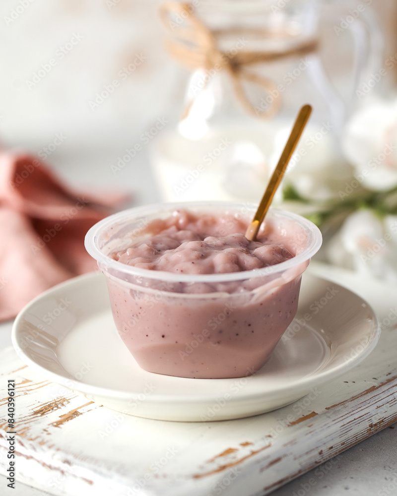 Currant whey dessert with spoon in plastic cup on board