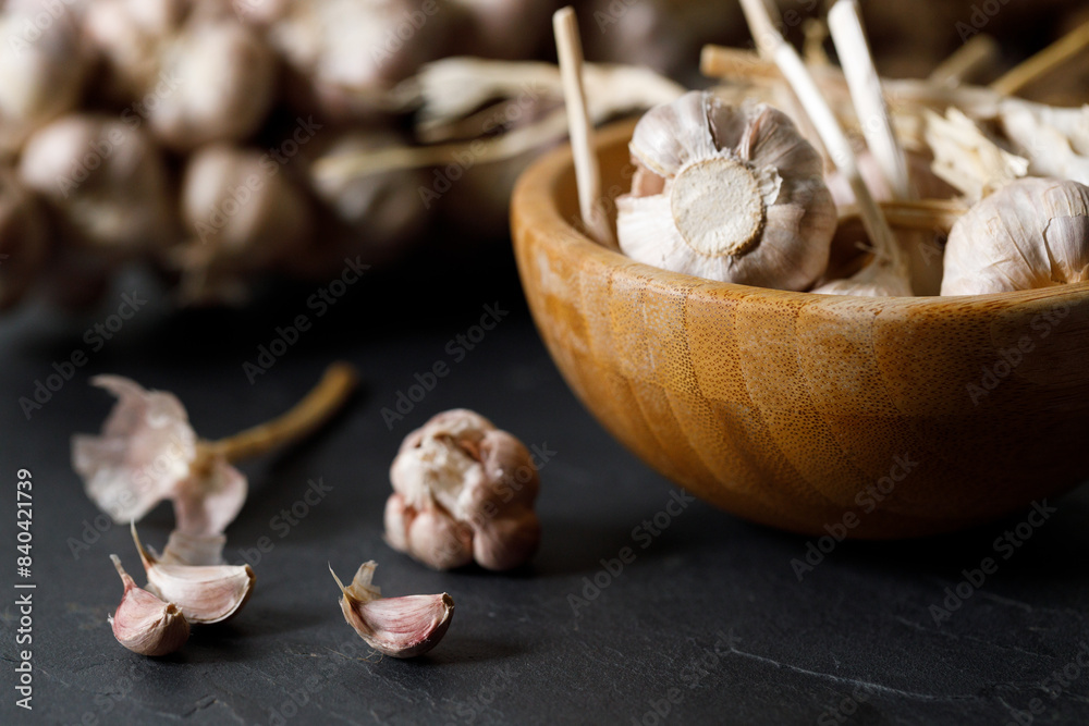 Ripe organic garlic clove and bulb on black stone background. Close-up. Selective focus. Ripe organic garlic clove and bulb on black stone background. Close-up. Selective focus.
