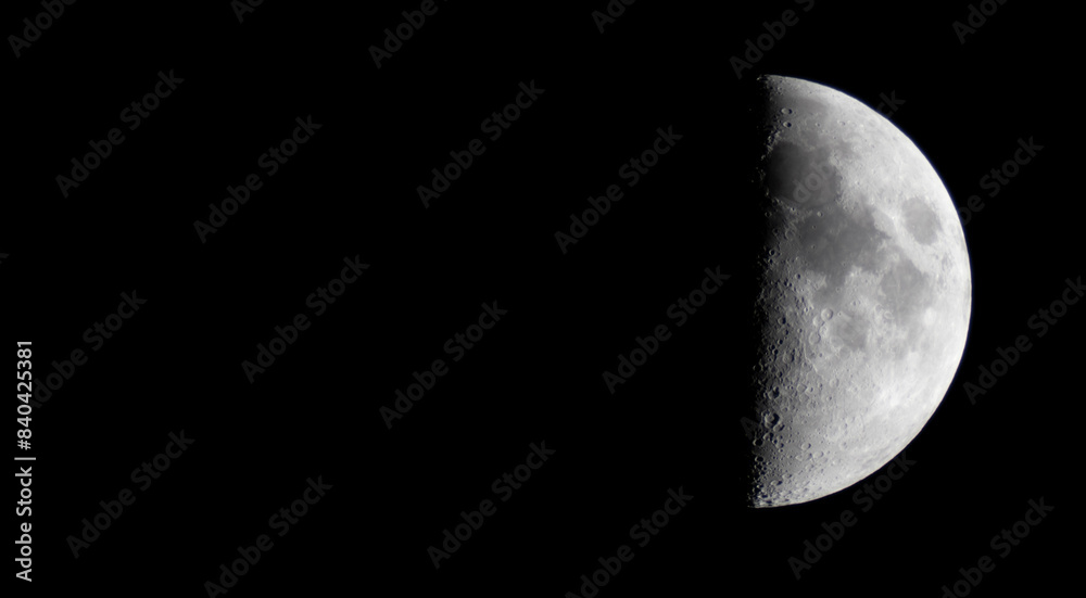 Half moon during the first quarter phase isolated against a black sky.