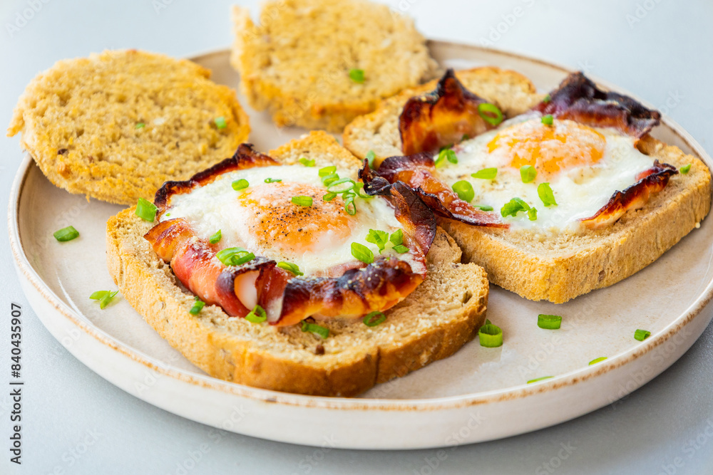 Baked Bacon and Eggs in Bread on White Plate with Fresh Green Onion Close-Up Baked Bacon and Eggs in Bread on White Plate with Fresh Green Onion Close-Up