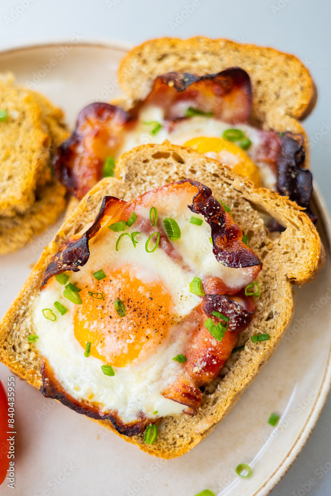 Baked Bacon and Eggs in Bread on White Plate with Fresh Green Onion Close-Up Baked Bacon and Eggs in Bread on White Plate with Fresh Green Onion Close-Up