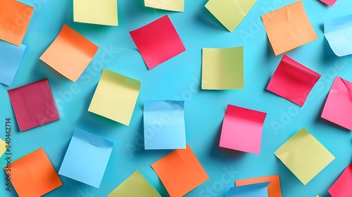 Colorful sticky notes scattered on a blue background in a flat lay. An abstract concept of a working process or business plan with colored sticky post-it cards.