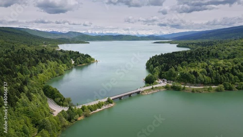 flight over lake in mountains, bridge on lake with forest banks, aerial view photo