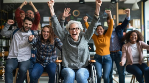 Candid photo of a diverse business team celebrating with a happy woman in a wheelchair  in an office meeting room background. A journey to success concept