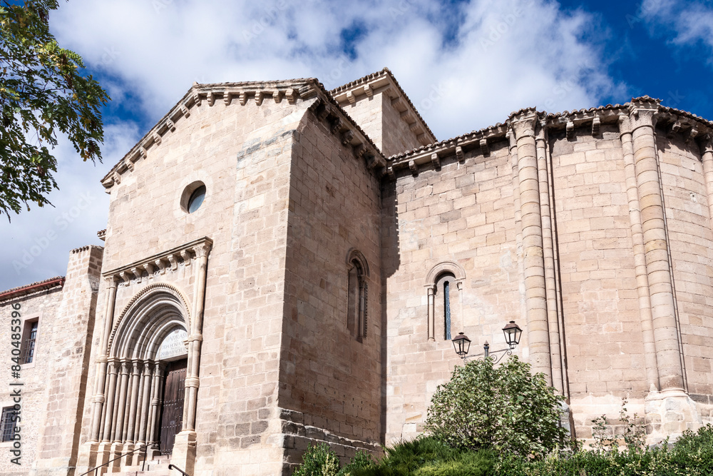 an ancient stone church with intricate details, set against a blue sky with clouds and greenery in molina de aragon an ancient stone church with intricate details, set against a blue sky with clouds and greenery in molina de aragon