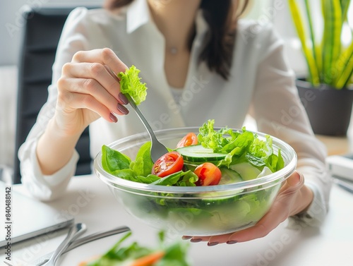 Young woman eating a salad in office. Young businesswoman sitting from desk.