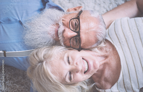 Senior couple lifestyle moments at home. Happy old woman and man laughing and havin fun on the carpet. photo