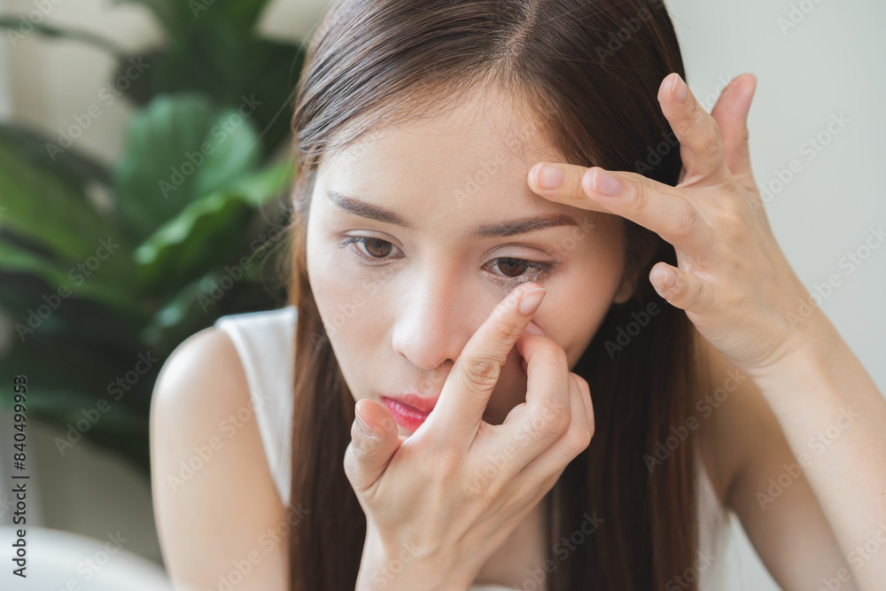 Ophthalmology care, eyesight or vision. Asian young woman, girl hand holding and putting, wearing soft, daily disposable contact lens on her face with finger, looking into eye. Medical and health care Ophthalmology care, eyesight or vision. Asian young woman, girl hand holding and putting, wearing soft, daily disposable contact lens on her face with finger, looking into eye. Medical and health care