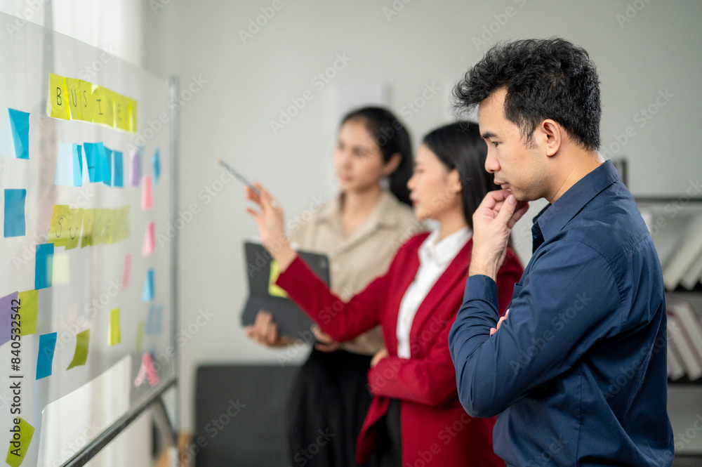 Obraz premium A man is looking at a board with a woman pointing at it