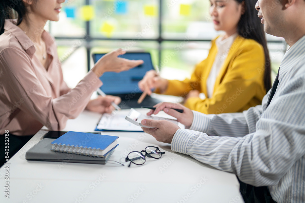 Three people are sitting at a table, talking and working Three people are sitting at a table, talking and working