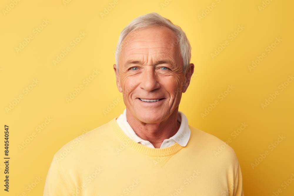 Portrait of a glad man in his 60s wearing a classic turtleneck sweater in front of pastel yellow background Portrait of a glad man in his 60s wearing a classic turtleneck sweater in front of pastel yellow background