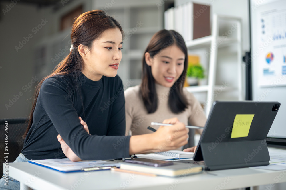 Two women are working on a project together, one of them is pointing at a laptop Two women are working on a project together, one of them is pointing at a laptop