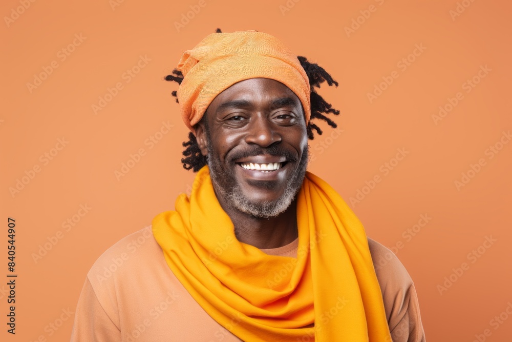 Portrait of a happy afro-american man in his 40s wearing a versatile buff while standing against pastel orange background Portrait of a happy afro-american man in his 40s wearing a versatile buff while standing against pastel orange background