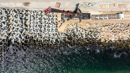Aerial view of breakwater construction. Crane puts tetrapods on breakwater construction photo