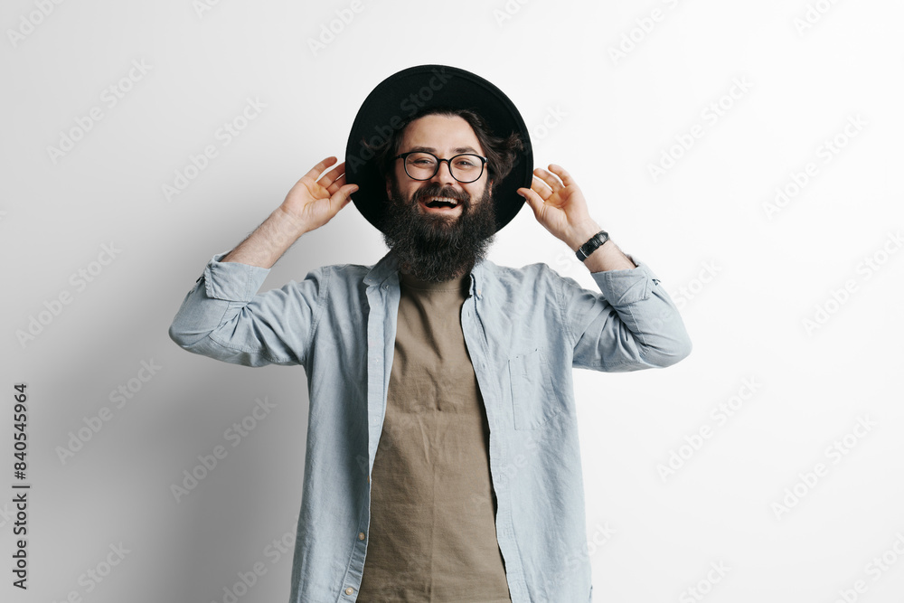 A well-dressed man in casual attire holds a hat in front of him against a clean white background, exuding a sense of mystery, fashion, and anonymity. A well-dressed man in casual attire holds a hat in front of him against a clean white background, exuding a sense of mystery, fashion, and anonymity.