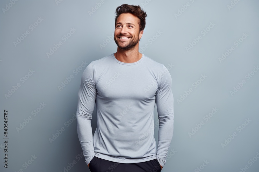 Portrait of a happy man in his 30s showing off a lightweight base layer in pastel gray background Portrait of a happy man in his 30s showing off a lightweight base layer in pastel gray background