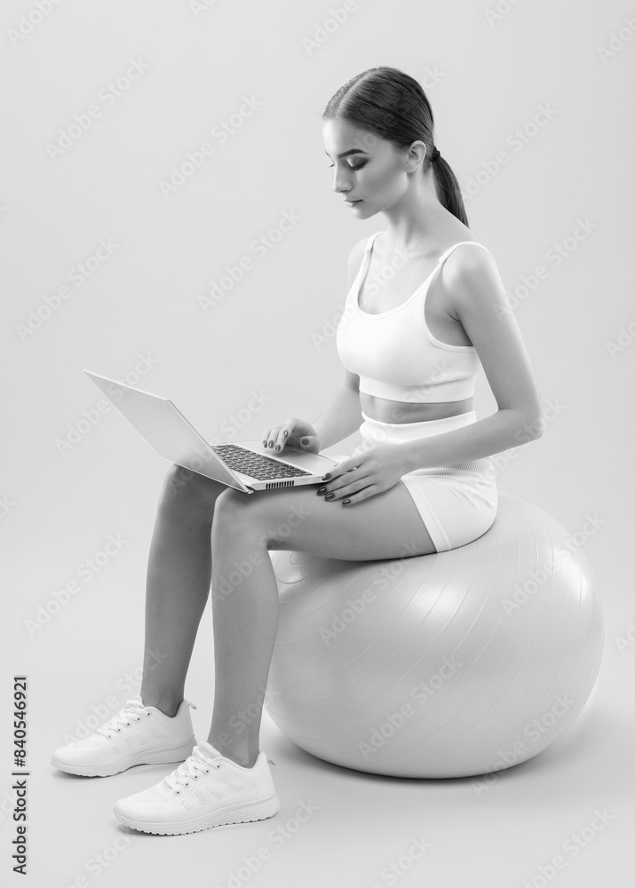 Obraz premium Slender dark-skinned female blogger in a white tracksuit against a white background. Healthy lifestyle, sports and diet.