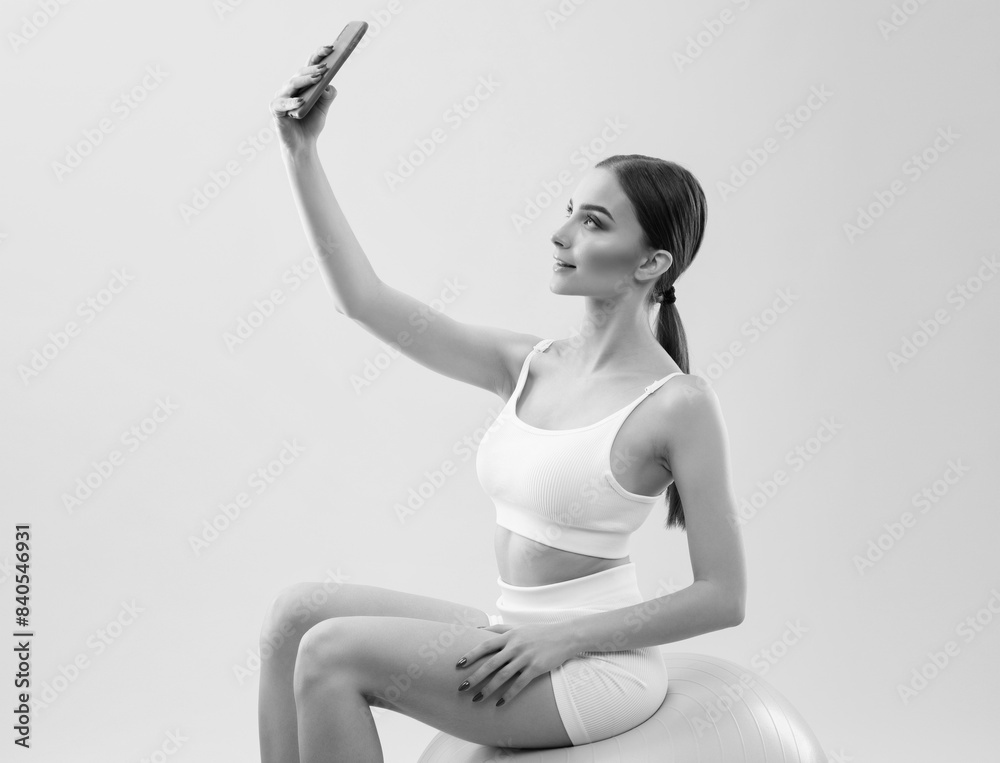 Naklejka premium Slender dark-skinned female blogger in a white tracksuit against a white background. Healthy lifestyle, sports and diet.