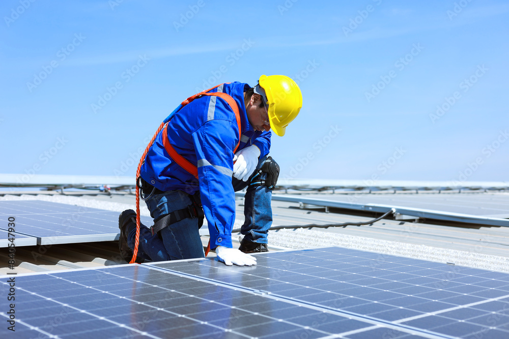Caucasian engineer puts hand on solar panels to test pressure on factory roof. Caucasian engineer puts hand on solar panels to test pressure on factory roof.