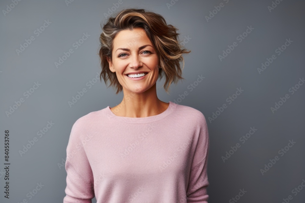 Portrait of a smiling woman in her 40s showing off a thermal merino wool top in pastel gray background Portrait of a smiling woman in her 40s showing off a thermal merino wool top in pastel gray background