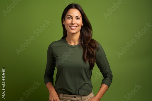 Portrait of a blissful woman in her 30s sporting a breathable hiking shirt over soft green background