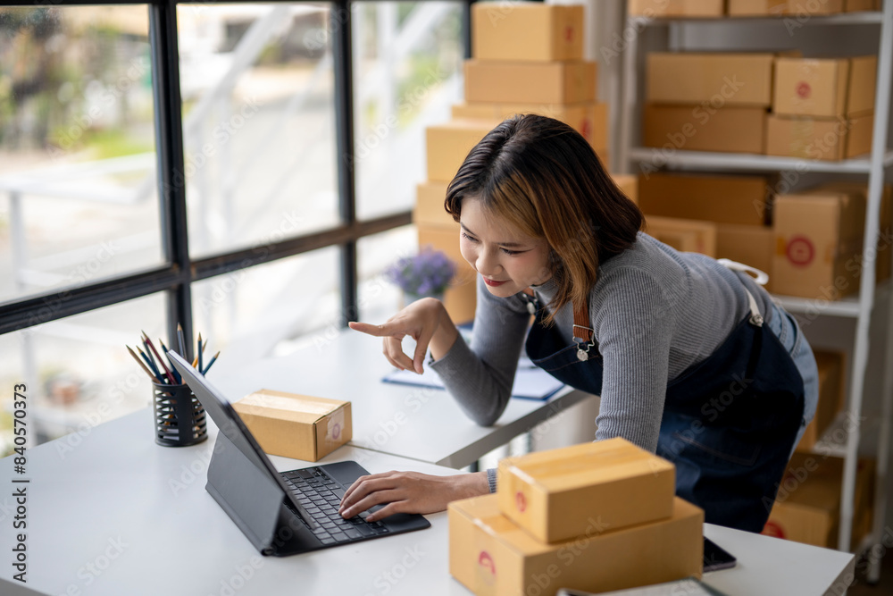A woman is sitting at a desk with a laptop and a box of boxes behind her A woman is sitting at a desk with a laptop and a box of boxes behind her